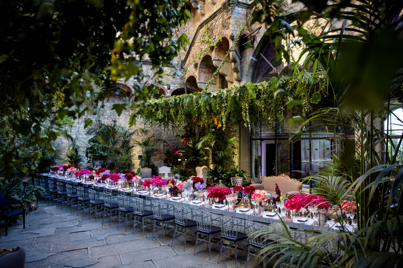 Long mirror table with hanging greenery and red and fuxia flowers