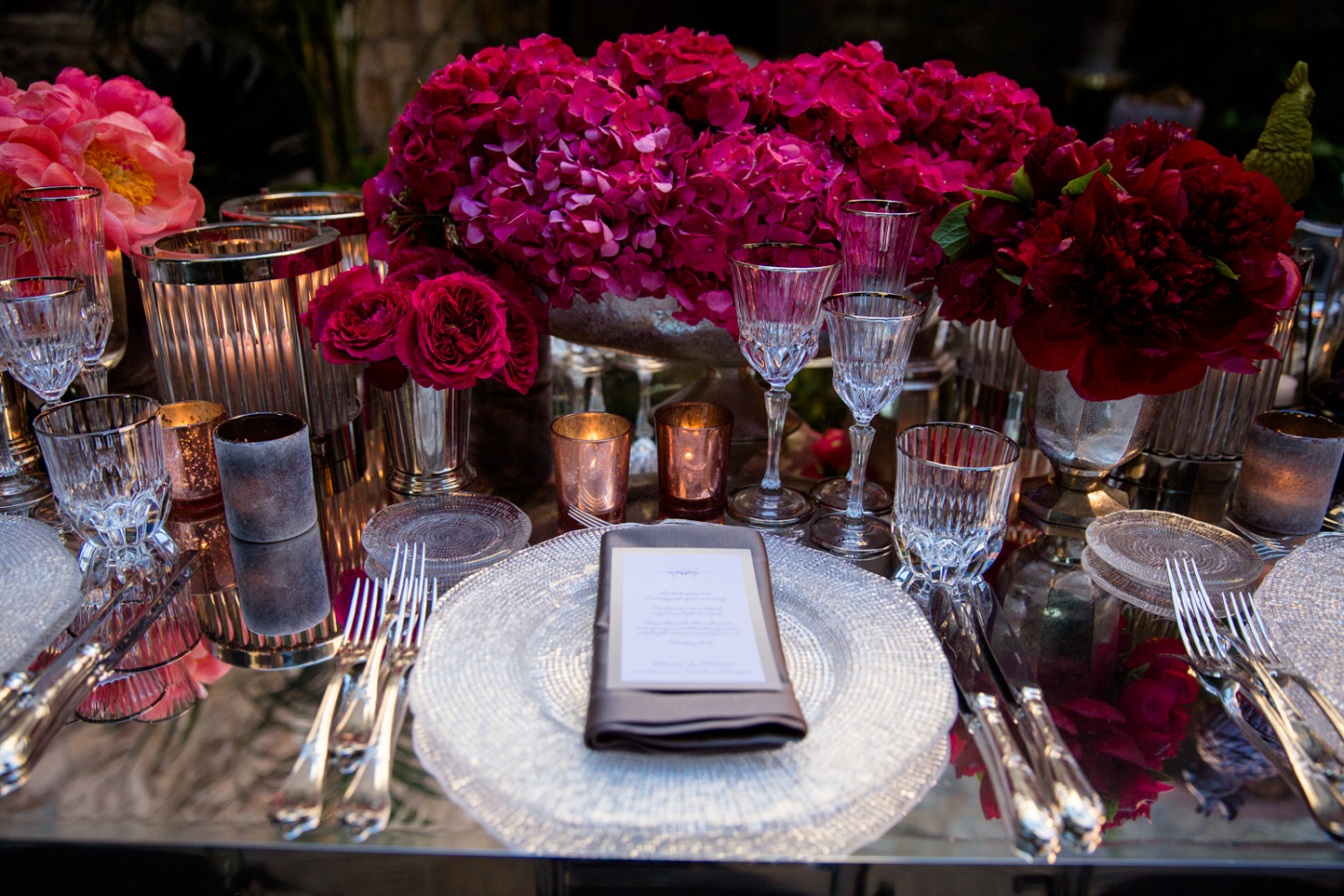 Elegant table setting with red and fuxia flowers and mirror table