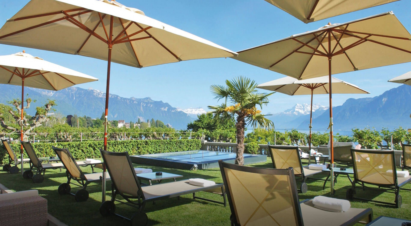 Pool garden with umbrellas and sunbeds in a luxury venue in Switzerland