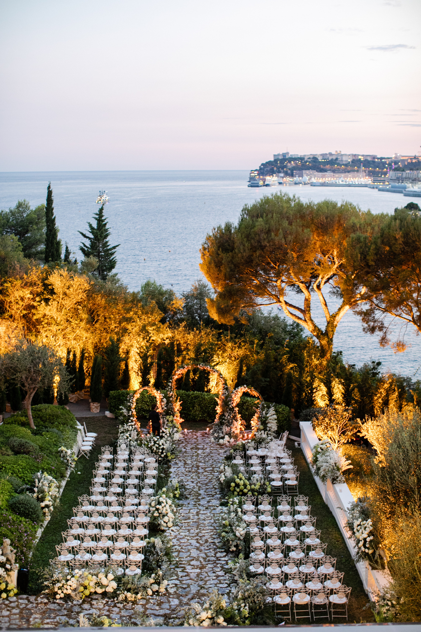 Outdoor ceremony with sea view and white decors and chairs