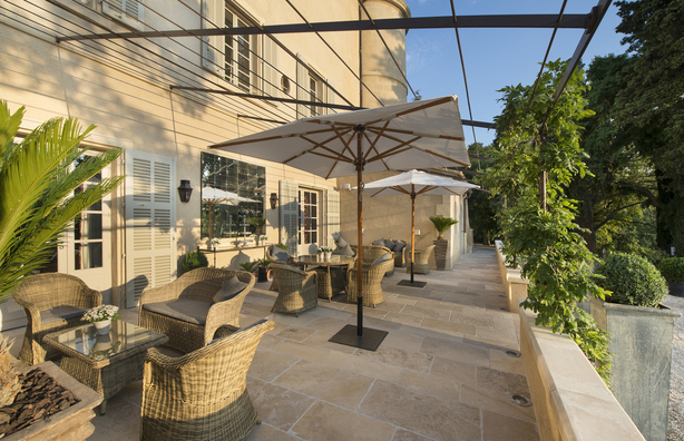 Shaded terrace with tables at luxury chateau d'Estoublon in Provence